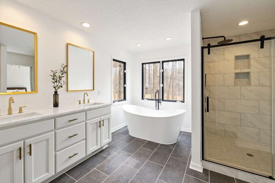 Modern bathroom interior featuring sleek dark grey floor tiles and a freestanding bathtub.