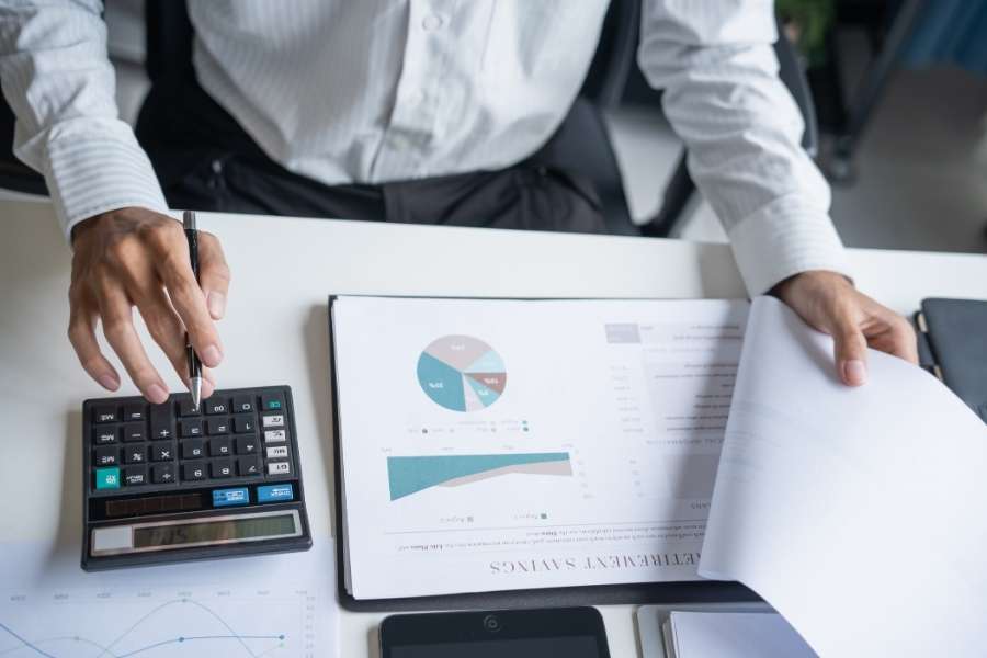 A financial professional calculating closing costs on a document with a calculator.