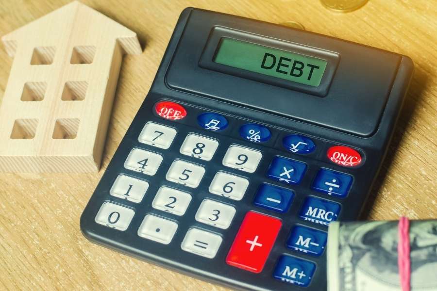 A black calculator displaying the word debt next to a model house for adjustable-rate mortgages.