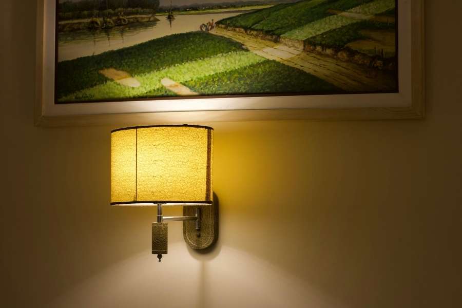 An illuminated wall sconce mounted below artwork demonstrating elegant wall light placement.
